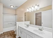 Thumbnail 67 of 67 - A bathroom with a white vanity and a large mirror.