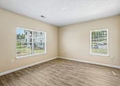 Thumbnail 61 of 67 - A room with light brown walls and wooden flooring with two windows.