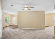 Thumbnail 56 of 67 - A spacious room with a ceiling fan and carpeted floor.