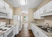 Thumbnail 55 of 67 - A kitchen with white appliances and cabinets.