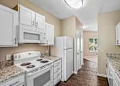 Thumbnail 51 of 67 - A kitchen with white appliances and cabinets.