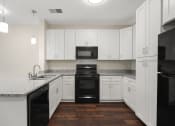 Thumbnail 2 of 27 - an empty kitchen with white cabinets and black appliances