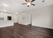 Thumbnail 3 of 27 - an empty living room with a ceiling fan and a kitchen
