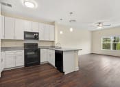 Thumbnail 6 of 27 - an empty kitchen with white cabinets and a black stove and refrigerator
