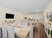 Thumbnail 23 of 27 - a dining room with tables and chairs and a living room with a tv