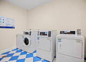 Thumbnail 14 of 27 - a laundry room with four washing machines and a blue and white checkered floor