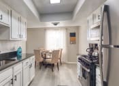 Thumbnail 22 of 52 - a kitchen with white cabinets and a sink and a table with chairs  at Bayville Apartments, Virginia Beach, VA