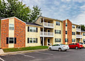 Thumbnail 4 of 13 - A parking lot with cars and apartment buildings.