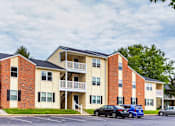Thumbnail 3 of 13 - Apartment building with cars parked in front.