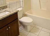 Thumbnail 12 of 13 - A white toilet sits in a bathroom next to a sink and a bathtub.