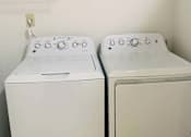 Thumbnail 11 of 13 - Two white washing machines in a laundry room.