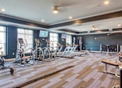 Thumbnail 7 of 24 - a fitness room with treadmills and weights on a wooden floor