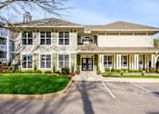 Thumbnail 18 of 20 - A large, two-story building with a front porch and a driveway in front.