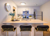 Thumbnail 1 of 20 - A kitchen with white countertops and black barstools.