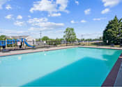 Thumbnail 3 of 36 - A large outdoor swimming pool with a slide in the background.