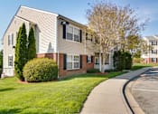 Thumbnail 12 of 36 - A residential building with a white and beige exterior and a green lawn in front.