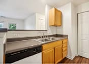 Thumbnail 15 of 36 - A kitchen with a black dishwasher and wooden cabinets.