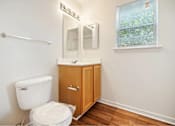 Thumbnail 18 of 36 - A white toilet sits next to a wooden cabinet in a bathroom.