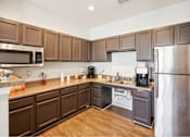 Thumbnail 33 of 36 - A kitchen with brown cabinets and a stainless steel refrigerator.