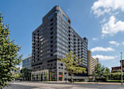 Thumbnail 55 of 55 - A large modern building with a lot of windows is surrounded by trees and other buildings.