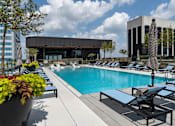 Thumbnail 29 of 55 - A pool area with lounge chairs and a building in the background.