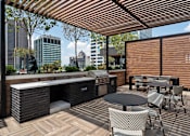 Thumbnail 25 of 55 - A patio with a grill and chairs overlooking a city skyline.