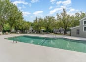 Thumbnail 35 of 43 - a swimming pool with trees and buildings in the background at Village 1373, Greensboro, NC