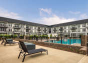 Thumbnail 54 of 81 - a swimming pool with lounge chairs in front of an apartment building at Ainsworth, Richmond
