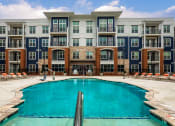 Thumbnail 25 of 42 - a swimming pool in front of an apartment building at The Bella at Westchester, Midlothian, VA