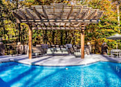 Thumbnail 55 of 67 - A pool with a wooden pergola over it.