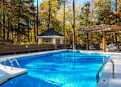 Thumbnail 53 of 67 - A swimming pool surrounded by trees and a gazebo.