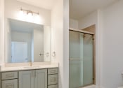 Thumbnail 47 of 47 - a bathroom with a sink and a mirror and a shower at The Port at East Beach Apartments and Marina, Virginia