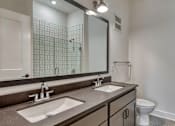 Thumbnail 11 of 29 - A bathroom with a white toilet, a sink, and a mirror at Aviator Lofts, Newport News, 23602