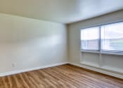 Thumbnail 18 of 24 - an empty room with wood flooring and two windows at Gates of West Bay in VA 23503