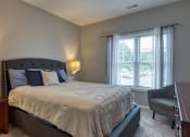 Thumbnail 19 of 44 - A bedroom with a large bed, a chair, and two lamps.