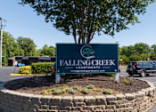 Thumbnail 27 of 31 - A sign for Falling Creek Apartments is displayed in front of a tree and a parking lot.