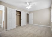Thumbnail 19 of 33 - an empty living room with white doors and a ceiling fan
