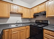 Thumbnail 15 of 33 - an empty kitchen with wood cabinets and black appliances