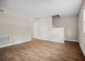 Thumbnail 25 of 33 - the living room of an apartment with wood flooring and a staircase
