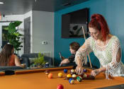 Thumbnail 22 of 60 - a woman playing a game of billiards on a pool table at Proximity at ODU in Norfolk, VA