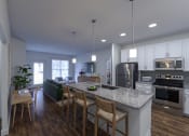 Thumbnail 21 of 42 - a kitchen and living room with white cabinets and a granite countertop at The Bella at Westchester, Midlothian, VA 23113