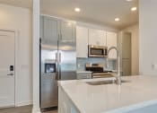 Thumbnail 25 of 47 - a kitchen with stainless steel appliances and white cabinets at The Port at East Beach Apartments and Marina, Virginia