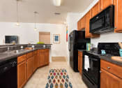 Thumbnail 3 of 32 - a kitchen with black appliances and wooden cabinets at Addison Crater Woods, Virginia, 23805
