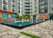 Thumbnail 11 of 40 - A pool surrounded by a concrete patio and a colorful mural on the wall.
