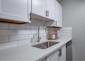 Thumbnail 9 of 18 - A kitchen with white cabinets and a stainless steel sink.