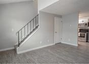 Thumbnail 13 of 18 - A room with a staircase and a door leading to a kitchen.