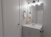 Thumbnail 17 of 18 - A bathroom with a white sink and a mirror with lights above it.