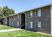 Thumbnail 7 of 16 - A building with a grey siding and a white door is shown.