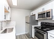 Thumbnail 2 of 16 - A kitchen with a stove, refrigerator, and microwave.
