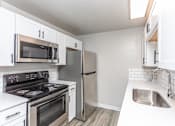 Thumbnail 10 of 16 - A kitchen with white cabinets and stainless steel appliances.